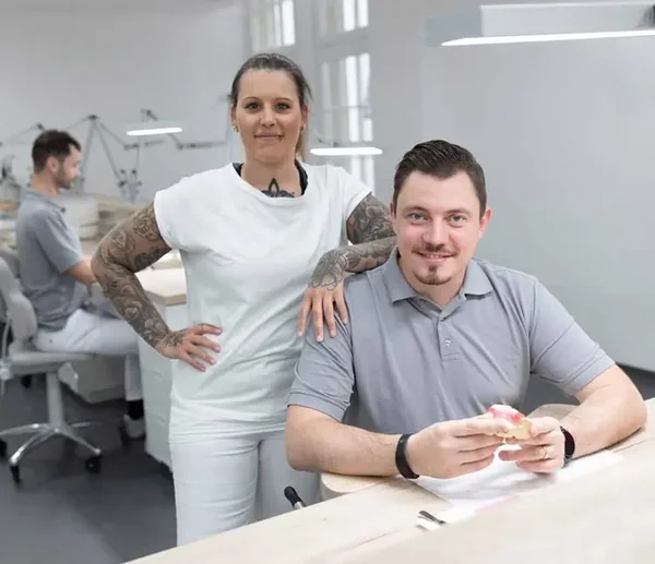 Zahnärztin und Zahntechniker besprechen ein Modell an einem Arbeitsplatz im Labor