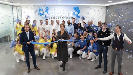 Teamfoto AllDent Zahnzentrum Bochum im Konfettiregen und mit Er&ouml;ffnungsband